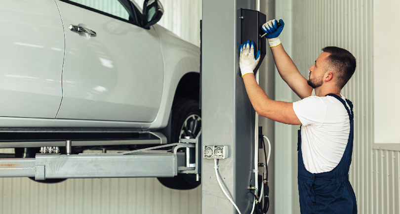 An asset-backed enclosed vehicle carrier transporter loading a premium SUV using an automated hydraulic lift gate.